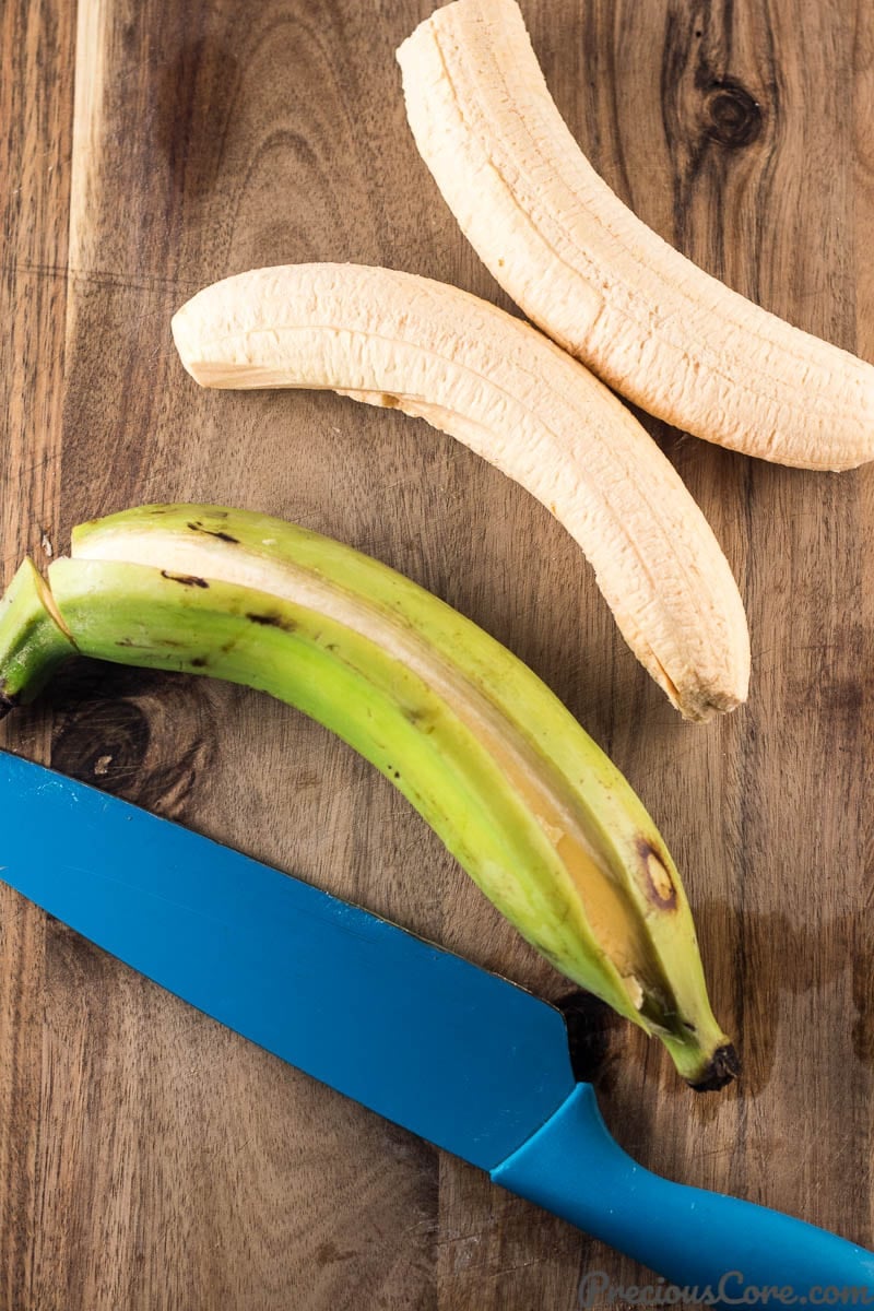 Knife with a plantain whose peel has been cut and two peeled plantains.