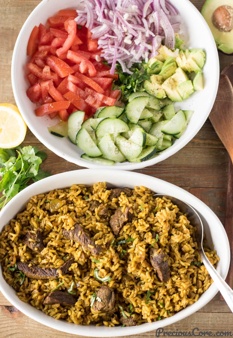 Bowl of Beef Pilau next to a bowl of vegetables.