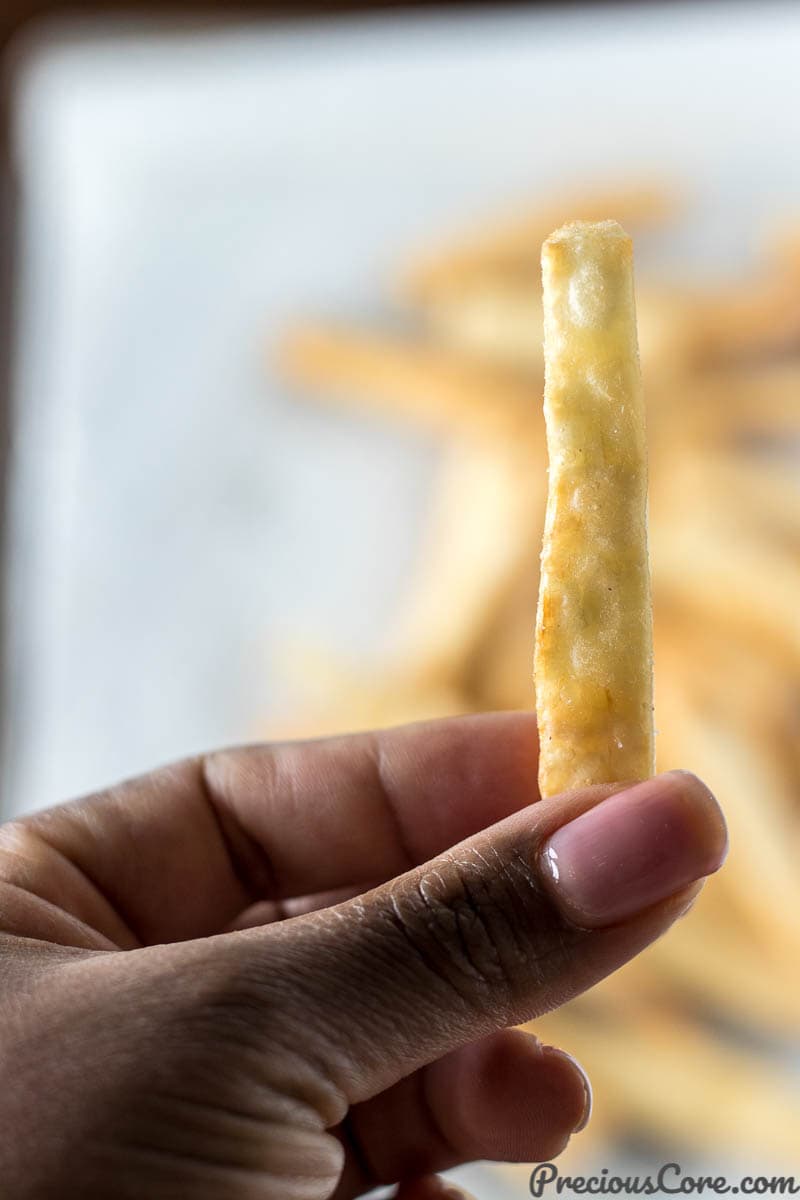 Hand holding a crispy yuca fry