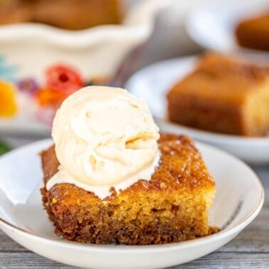 A slice of Malva Pudding topped with a scoop of ice cream.