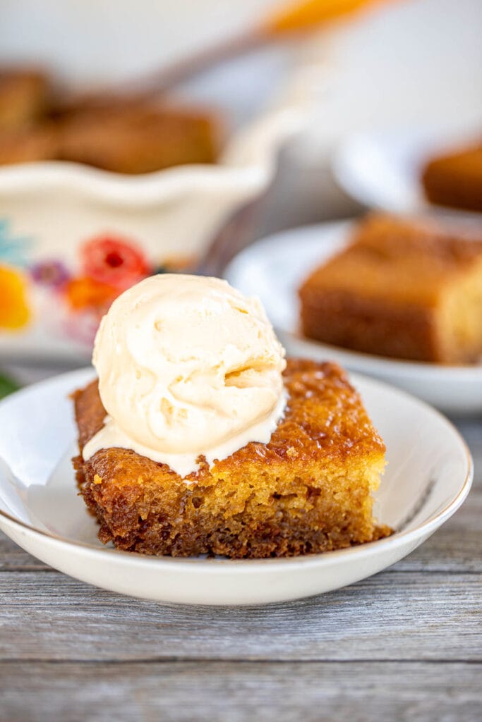 A slice of Malva Pudding topped with a scoop of ice cream.