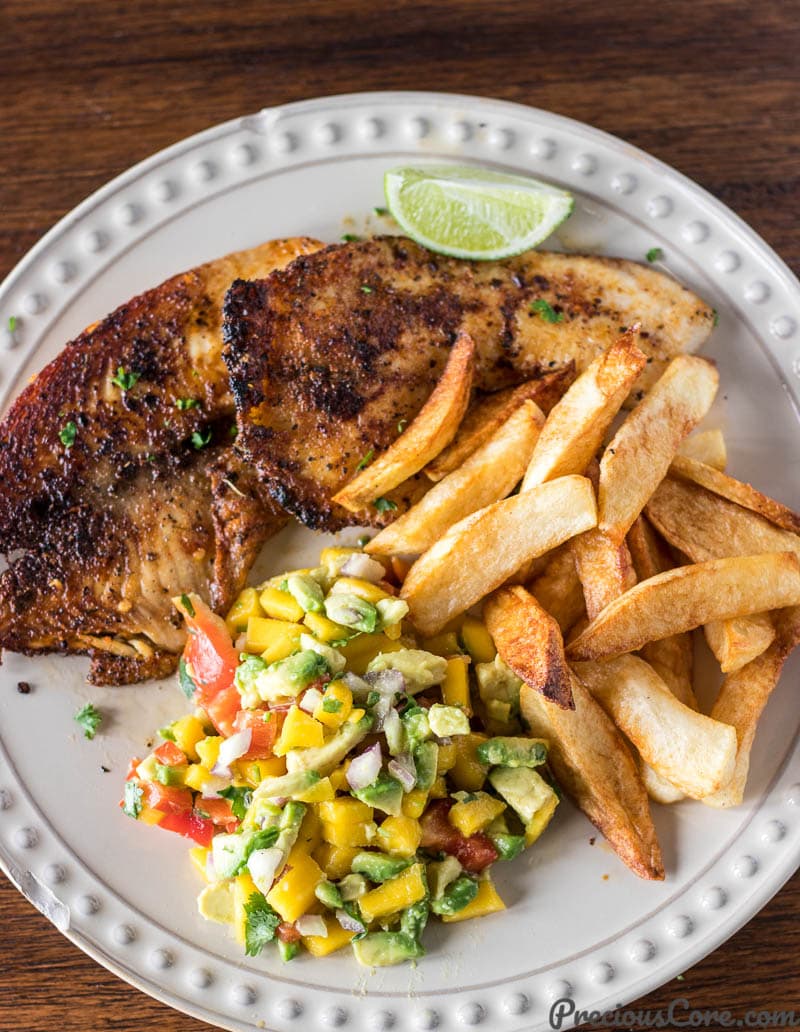 Mango Avocado Salsa on a plate with fries, grilled fish and a lime wedge