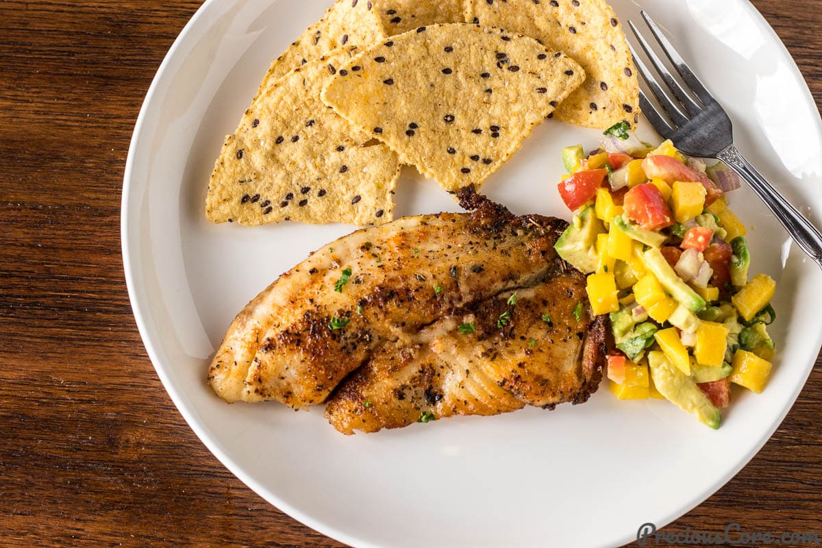 Pan Seared Tilapia on a plate with Mango Avocado Salsa and tortilla chips