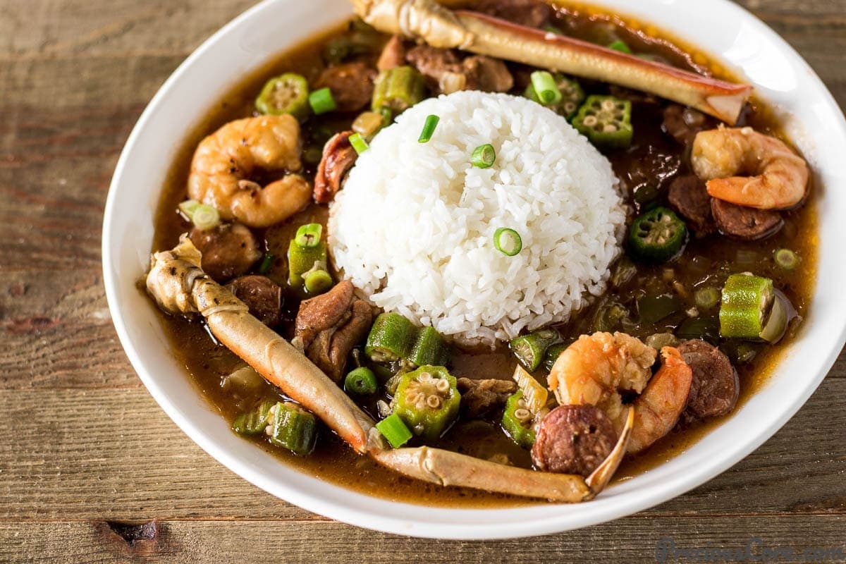 Seafood gumbo with shrimp and crab legs in a bowl with rice.