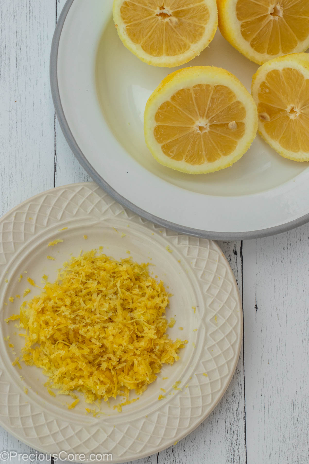 Lemon zest on one plate and lemon halves on another plate.