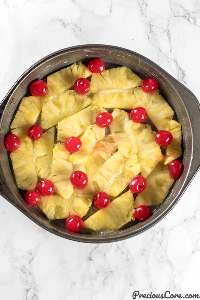 Pan layered with pineapples and cherries for Pineapple Upside Down Cake