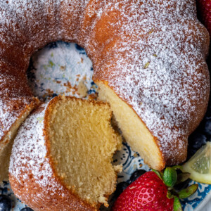 Lemon pound cake on a round platter with a piece of cake cut out.