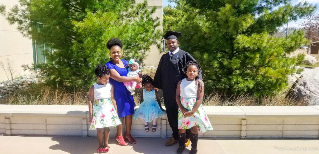 Man in graduation gear with a woman and four children.