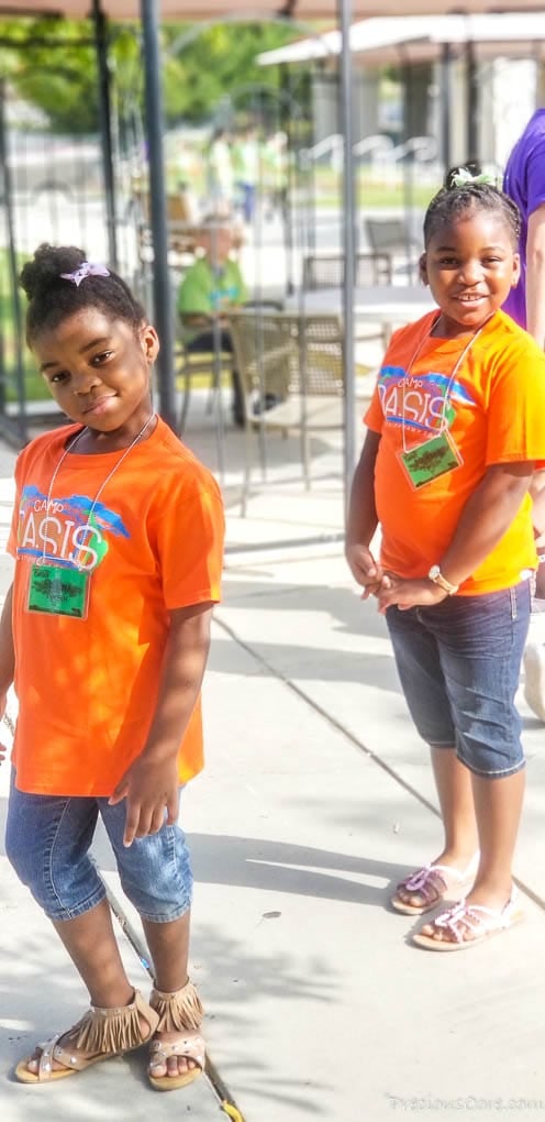 Two girls smiling in orange t-shirts.