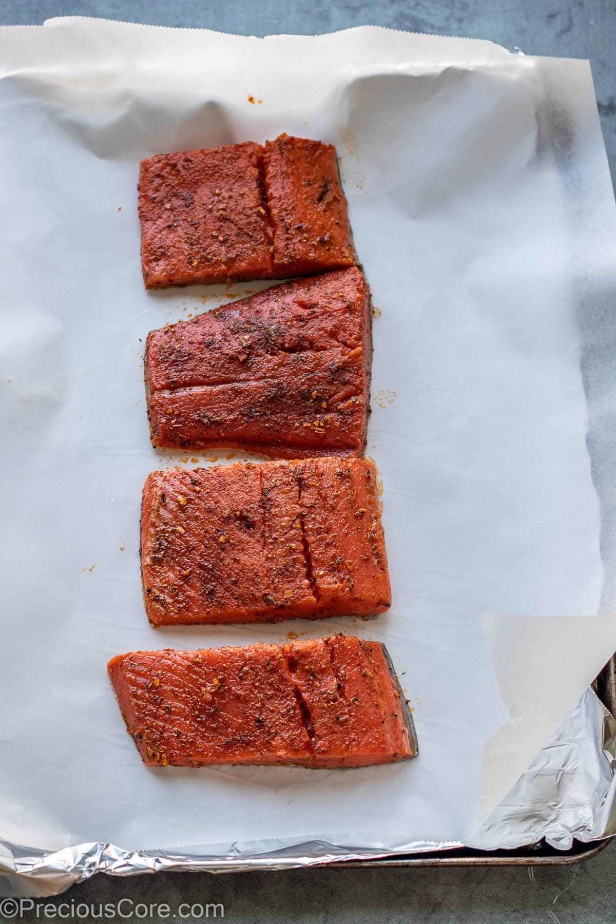 Seasoned cajun salmon placed on baking sheet for baking.