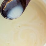 Spoon pouring bread pudding sauce