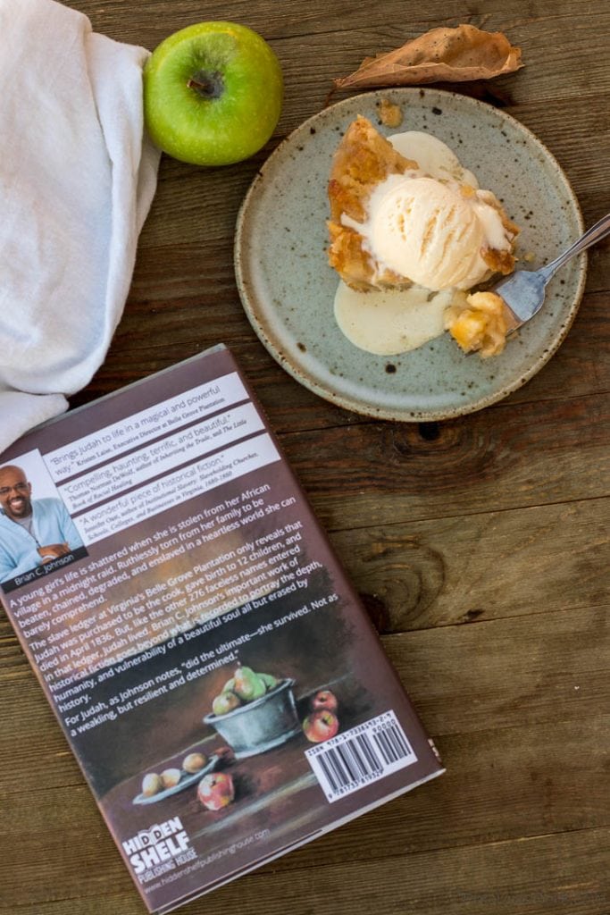 Apple pie on plate with melting ice cream in back, back of book in front.