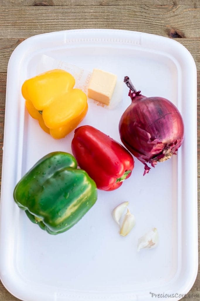 Colorful bell peppers on a tray with onions and garlic