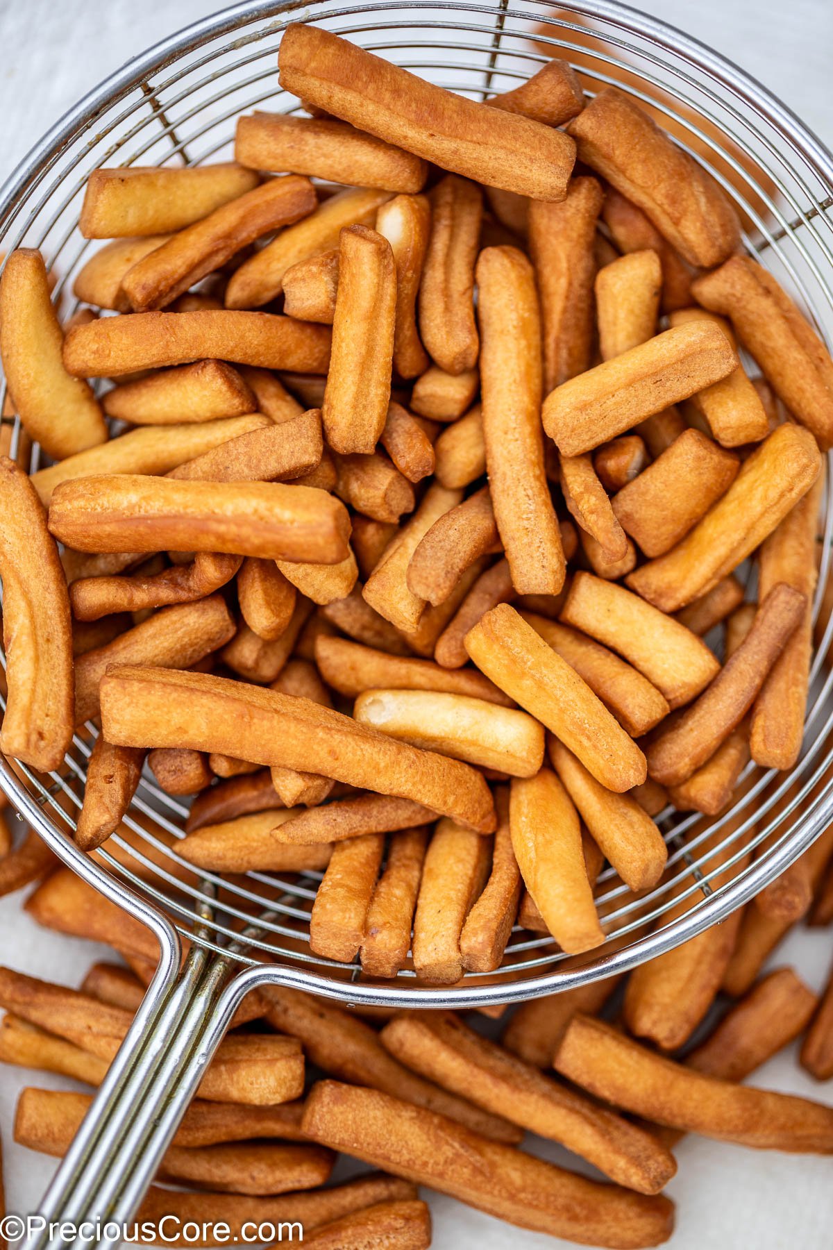 Golden brown fried chin chin in frying spoon.