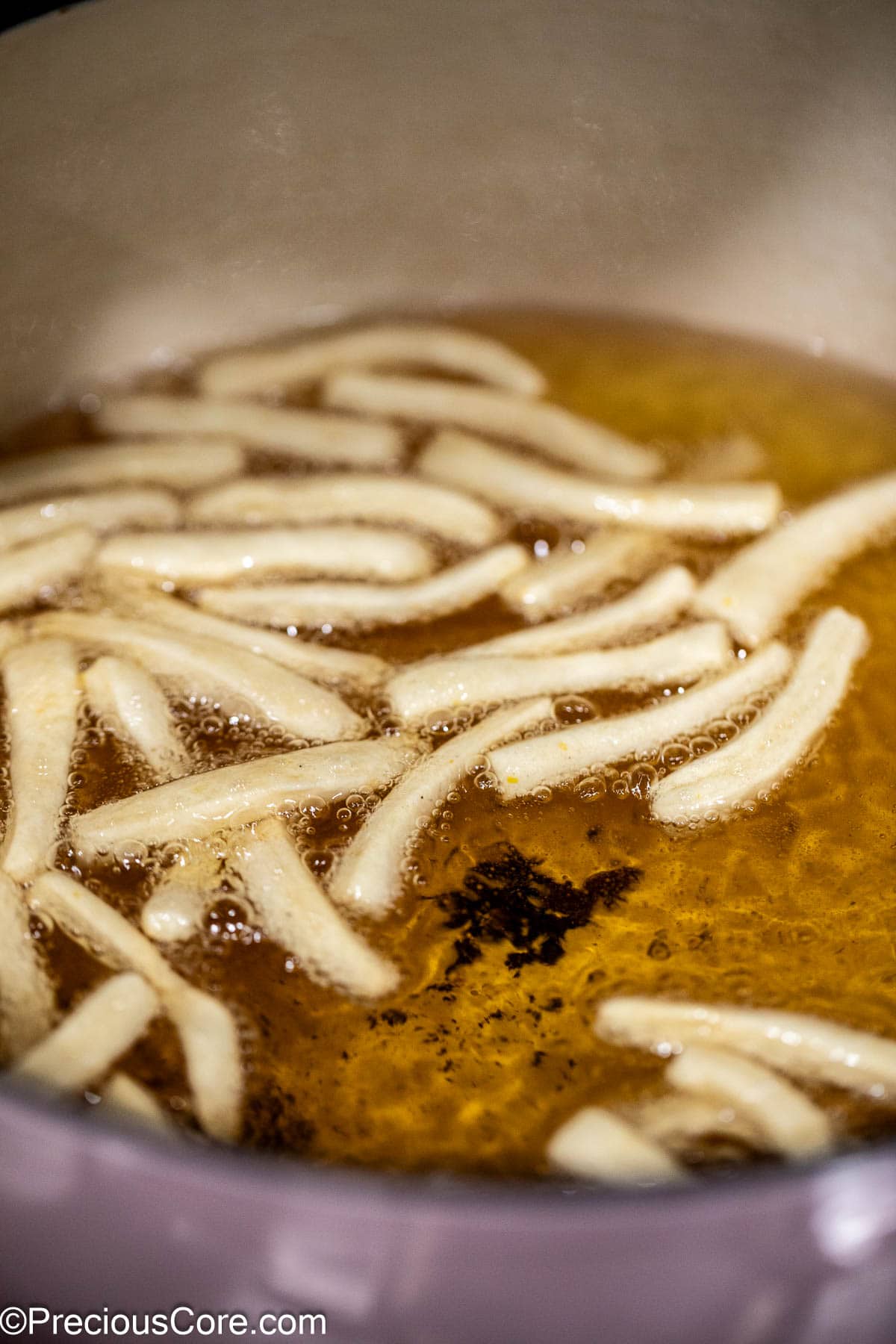 Dough strips frying in oil.