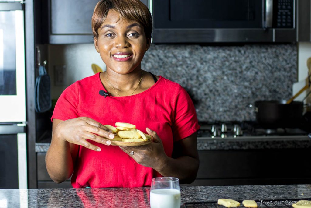 Black woman standing in kitchen holding a plate of cookies