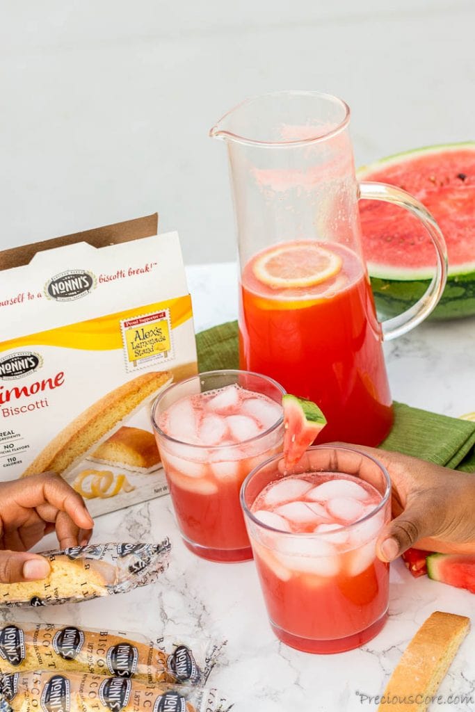 Hand holding a cup of watermelon lemonade, hand holding a cookie