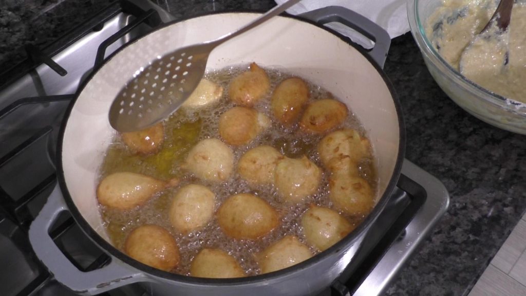 Banana fritters frying in a pot of hot oil