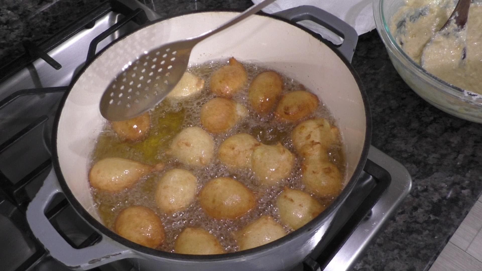 Fritters deep-frying in a cast iron pot. 