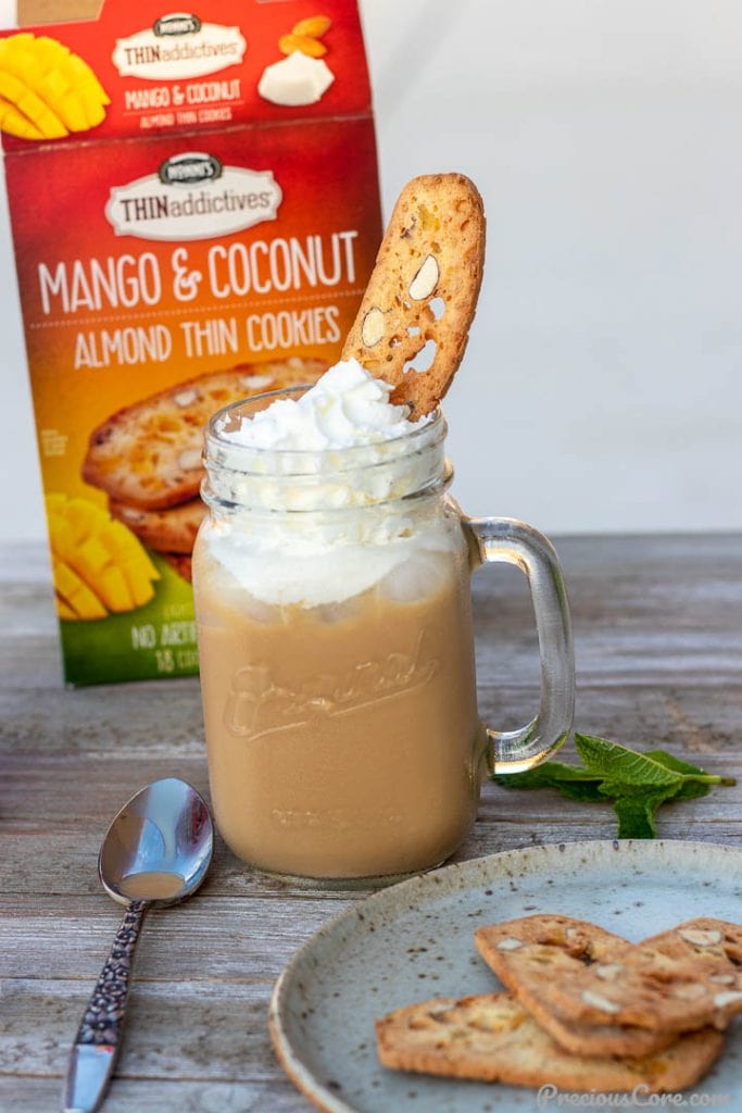 Iced coffee in a mason jar topped with whipped cream and a thin cookie