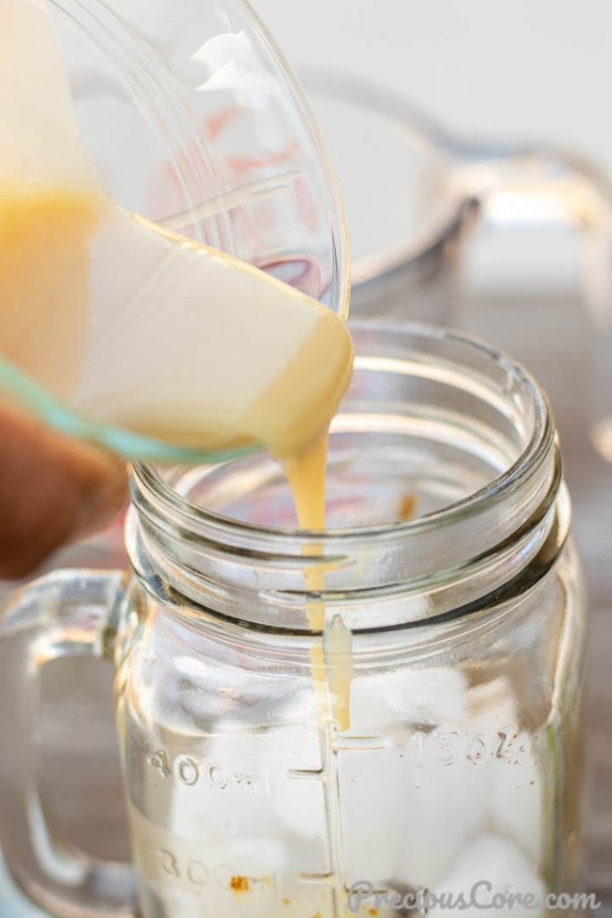 Sweetened condensed milk pouring into coffee cup