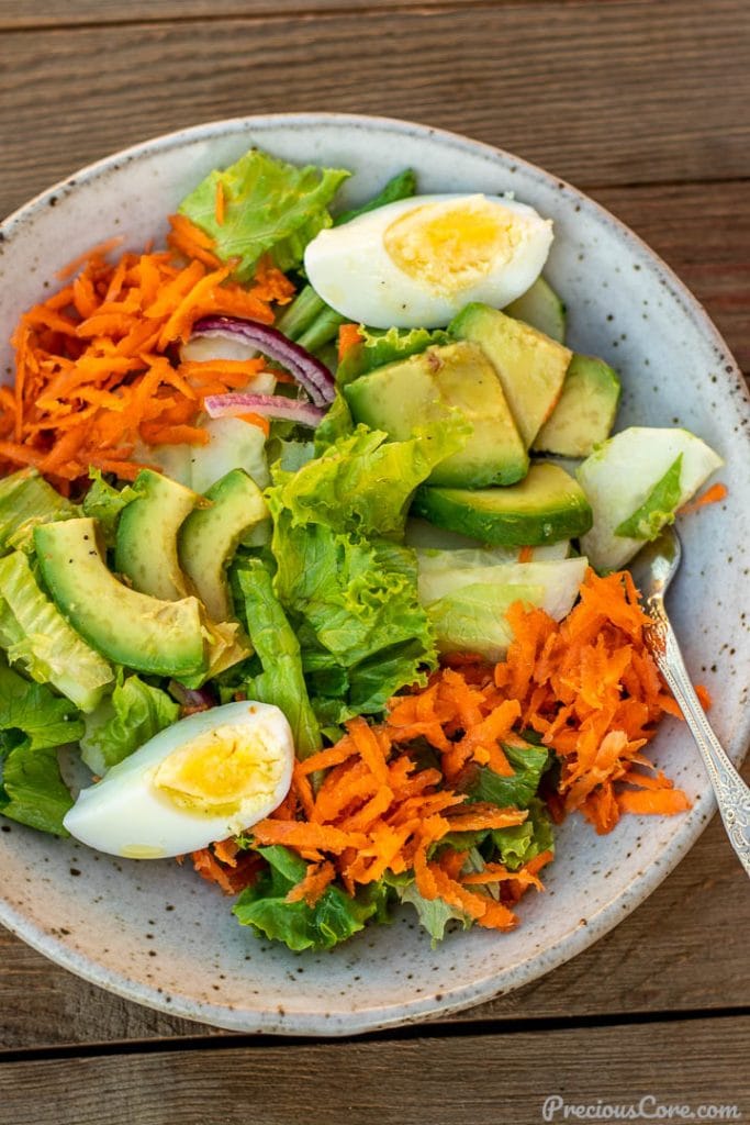 A serving of lettuce salad in a bowl with lemon dressing drizzled on top