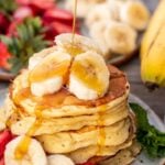 Stack of banana slices on a plate, banan slices on the stack and maple syrup pouring on top