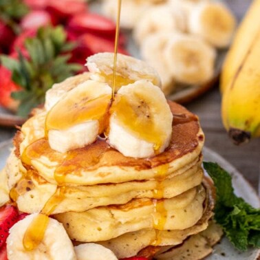 Stack of banana slices on a plate, banan slices on the stack and maple syrup pouring on top