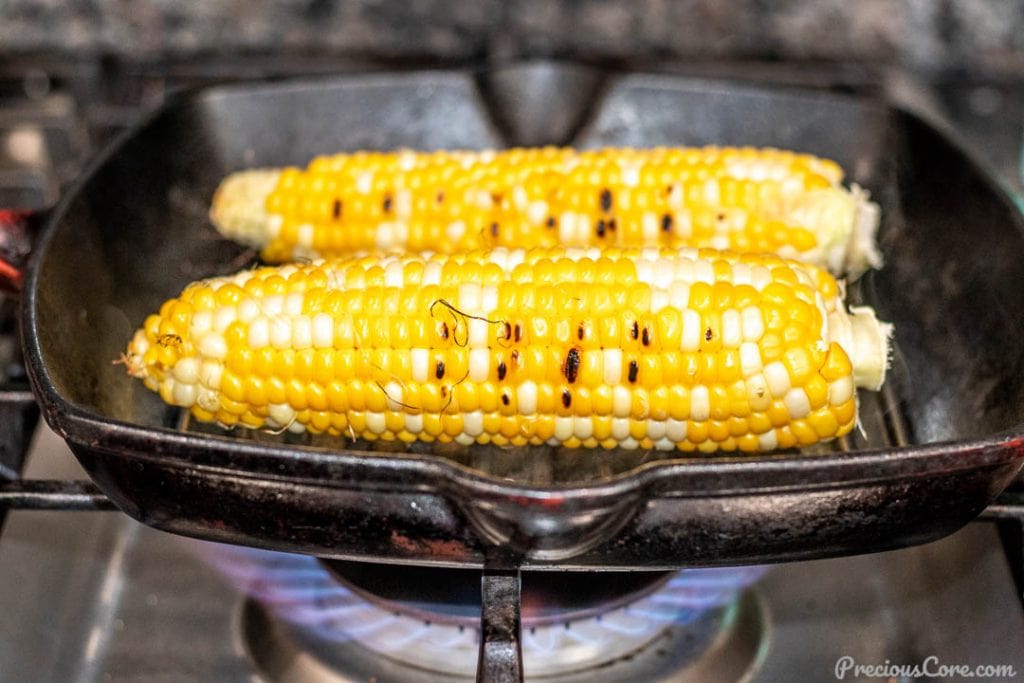 Corn on the cob grilling on grill pan on gas stove