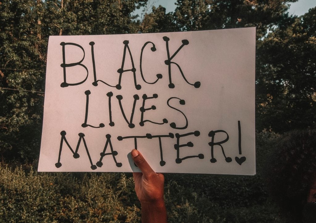 Black hand holding a "Black Lives Matter" placard