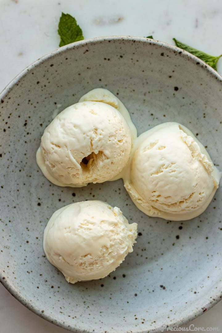 3 scoops of homemade vanilla ice cream in a bowl.