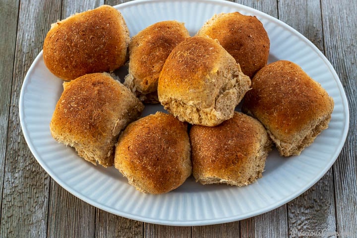 Whole wheat rolls on a white serving platter.
