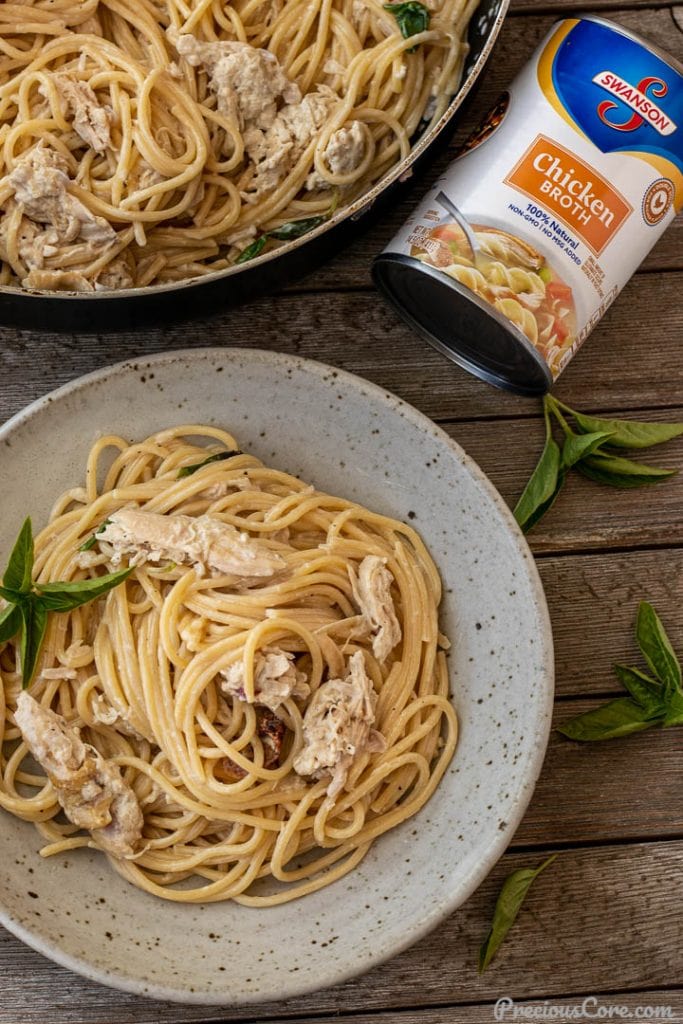 spaghetti and chicken in a bowl, can of chicken broth nearby