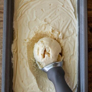 Vanilla ice cream in a load pan with scoop on top