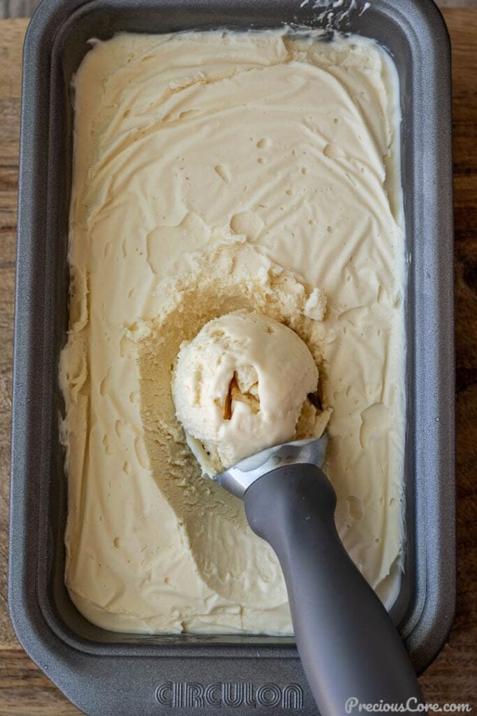 Vanilla ice cream in a load pan with scoop on top