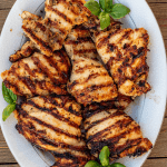 Grilled chicken thighs with grill marks garnished with basil