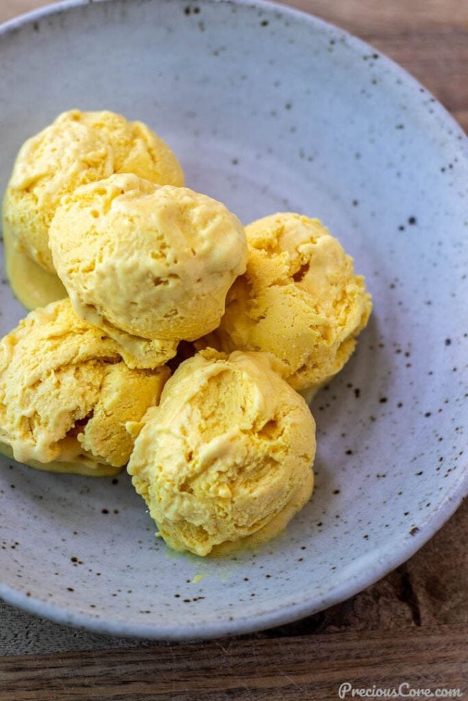 Scoops of mango ice cream in a bowl.