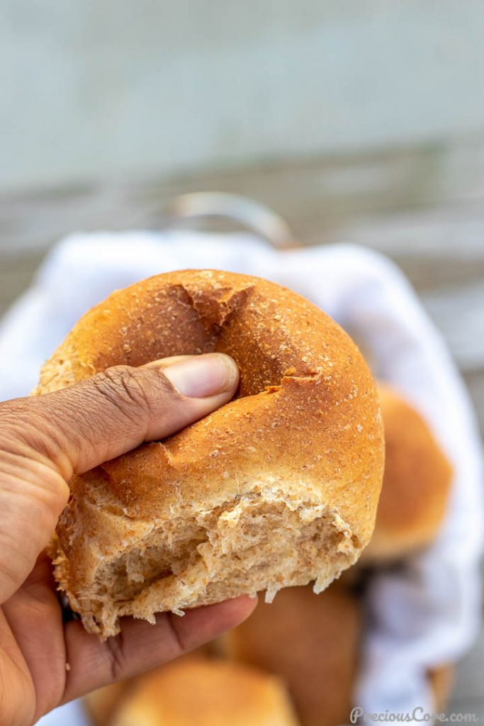 Hand pressing on a soft dinner roll.