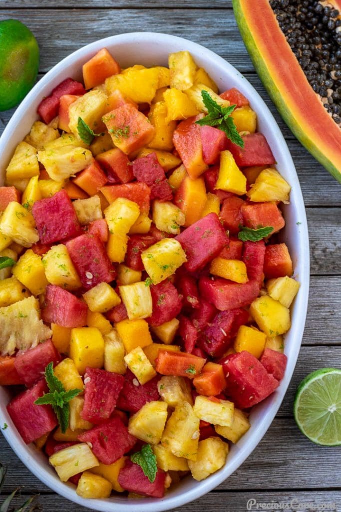 fruit salad in bowl, half a papaya and lime nearby