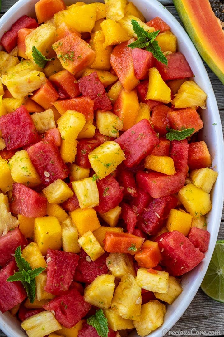 Tropical fruit salad in a white oval serving bowl.