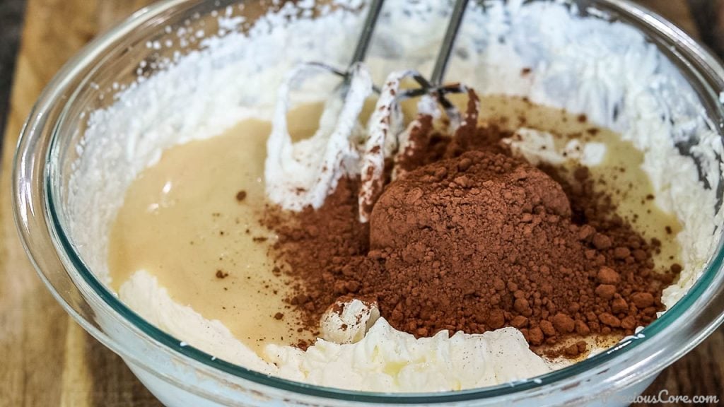 Cocoa powder added to bowl of whipped cream