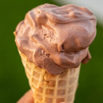 HAND HOLDING CONE OF CHOCOLATE ICE CREAM