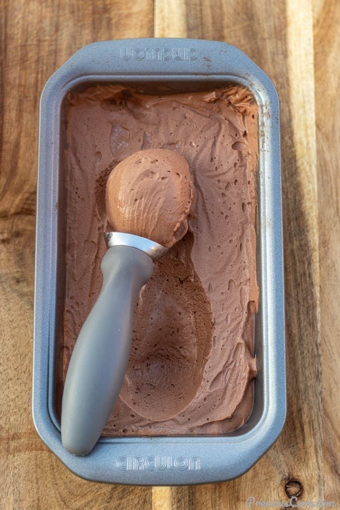 Scoop of ice cream in a loaf pan of chocolate ice cream