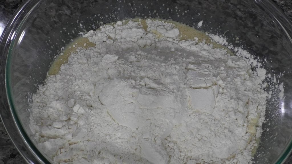 flour in a bowl with wet ingredients for dinner rolls