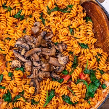 Pot of pasta in red sauce topped with mushrooms