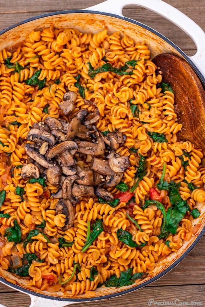 Pot of pasta in red sauce topped with mushrooms
