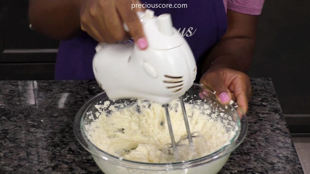 Hand holding electric beater beating butter and sugar