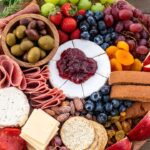 Round board filled with cheese, meats, cheese and crackers