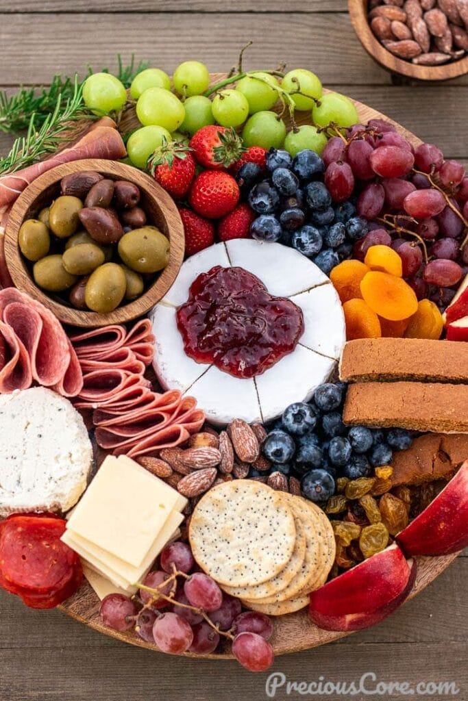 Round board filled with cheese, meats, cheese and crackers