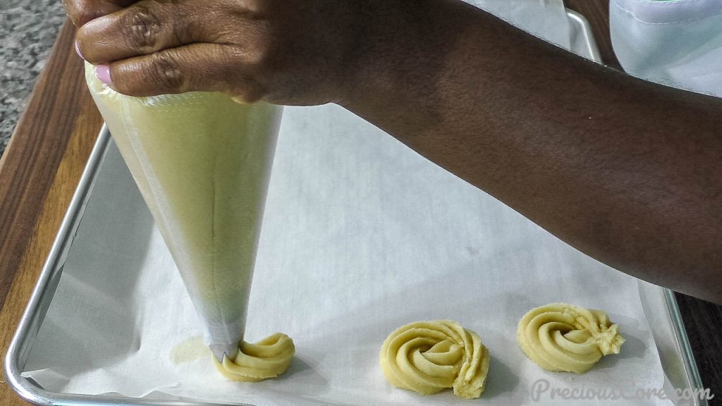 Hand piping butter cookies unto baking sheet